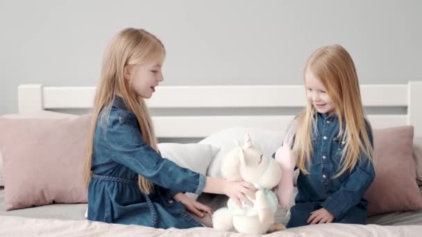 Две милые сестрички играют на кровати с подушками — стоковое видео