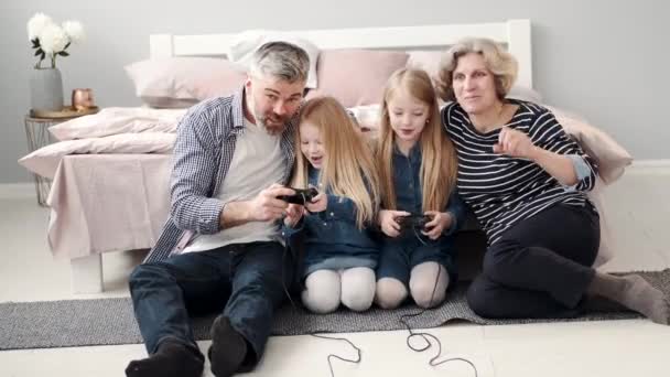 Två flickor spelar tv-spel med morföräldrar — Stockvideo