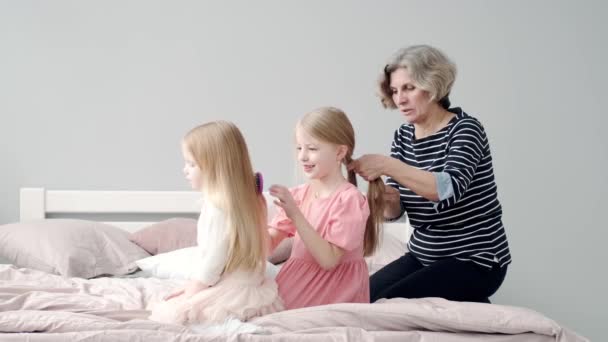 Snygg mormor fläta barnsligt hår i sovrummet — Stockvideo