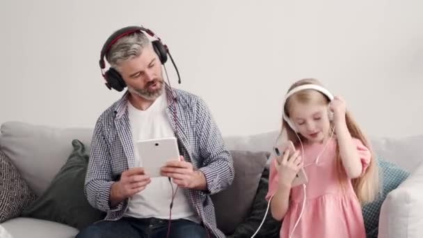 Liten flicka lyssnar musik i hörlurar med farfar — Stockvideo