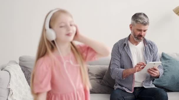 Liten flicka lyssnar musik i hörlurar med farfar — Stockvideo