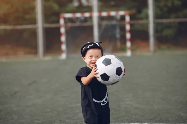Niño jugando al fútbol en un campo de deportes — Foto de Stock