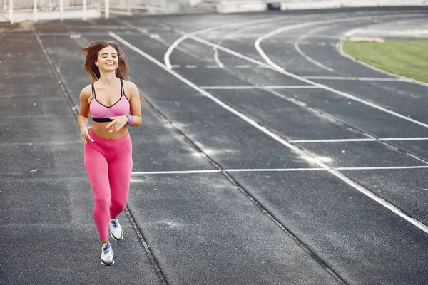 Ragazza sportiva in uniforme rosa corre allo stadio — Foto Stock