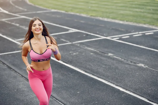 Menina de esportes em um uniforme rosa corre no estádio — Fotografia de Stock