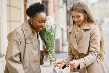 Alışveriş torbalarıyla sokaklarda dolaşan mutlu kızlar.