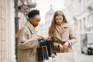 Alışveriş torbalarıyla sokaklarda dolaşan mutlu kızlar.