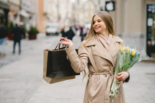 Elegante rubia de pie en la calle con flores —  Fotos de Stock