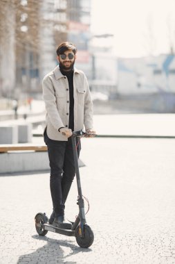 Tekmeleyen scooter süren pozitif gülümseyen adam.