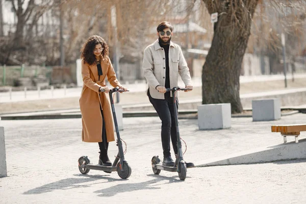 Interracial jovem casal com scooters no fundo da cidade — Fotografia de Stock