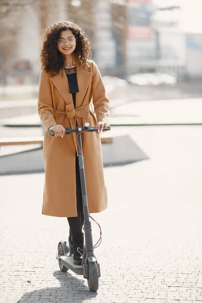 Tekmeli scooter süren pozitif gülümseyen bir kadın. — Stok fotoğraf