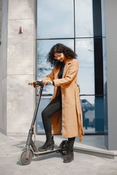 Tekmeli scooter süren pozitif gülümseyen bir kadın. — Stok fotoğraf