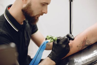 Dövme salonunda dövme yapan bir adam.