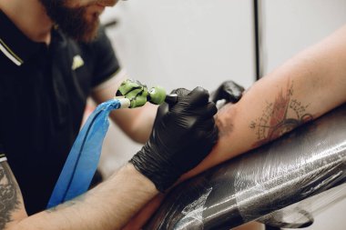Dövme salonunda dövme yapan bir adam.