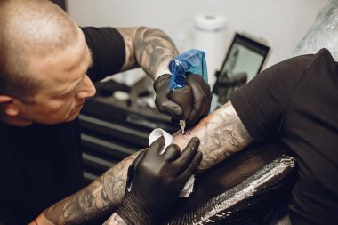 Dövme salonunda dövme yapan bir adam.