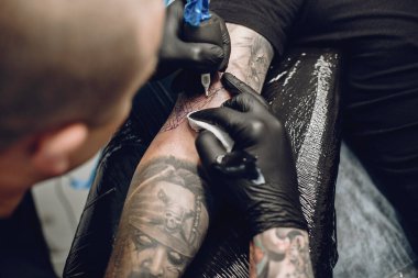 Dövme salonunda dövme yapan bir adam.