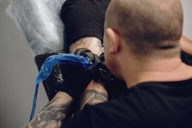 Dövme salonunda dövme yapan bir adam.