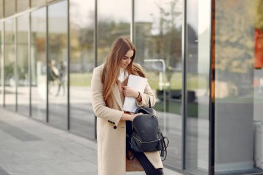 Bir bahar şehrinde duran ve elinde belgeler tutan bir kız.