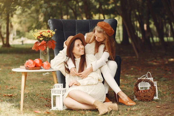 Элегантные и стильные девушки сидят на стуле в осеннем парке — стоковое фото