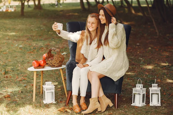 Элегантные и стильные девушки сидят на стуле в осеннем парке — стоковое фото