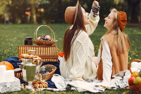 Элегантные и стильные девушки сидят в осеннем парке — стоковое фото