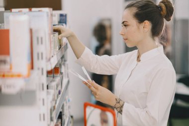 Kadın eczacı eczanede ilaç kontrolü yapıyor.
