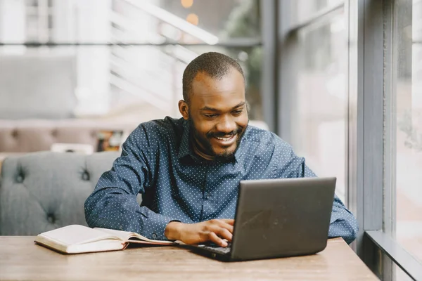 Homem trabalhando atrás de um laptop escrevendo em um notebook, café — Fotografia de Stock