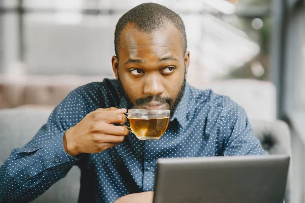 Homem sentado em um café e trabalhando atrás de um laptop e beber um chá. — Fotografia de Stock