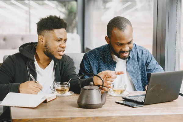 Dois homens sentados em um café e trabalhando atrás de um laptop e beber um chá. — Fotografia de Stock