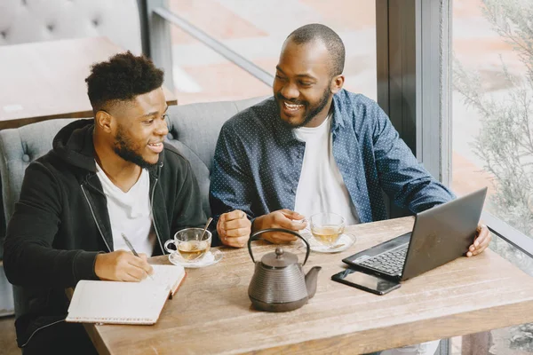 Dois homens sentados em um café e trabalhando atrás de um laptop e beber um chá. — Fotografia de Stock