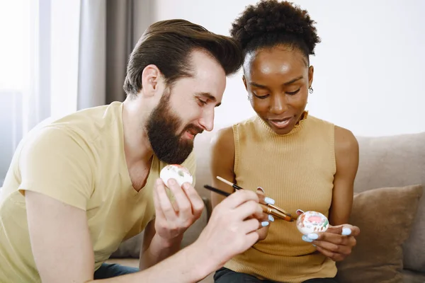 Afrikalı kadın ve beyaz adam Paskalya yumurtalarını boyuyor — Stok fotoğraf