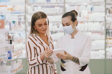 Kadın eczacı eczanede ilaç kontrolü yapıyor.