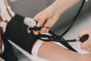 Stajyer eczanede müşterisinin kan basıncını ölçüyor.