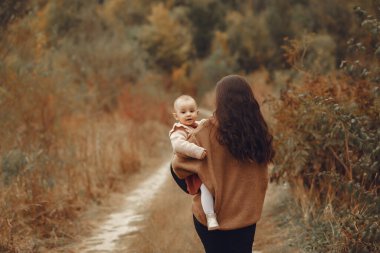 Anne ve küçük kızı sonbahar tarlasında oynuyorlar.