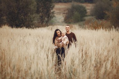 Sonbahar tarlasında oynayan sevimli ve şık bir aile.