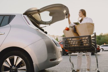 Elektrikli benzin istasyonunda kadın elektro arabayı şarj ediyor.