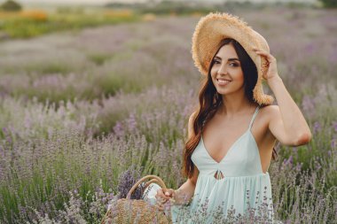 Genç bir kadın sepette lavanta topluyor.