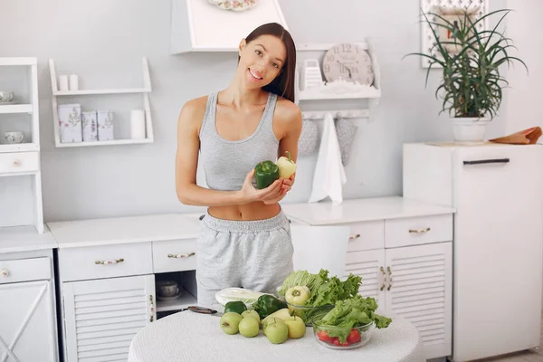Vacker och sportig flicka i ett kök med grönsaker — Stockfoto