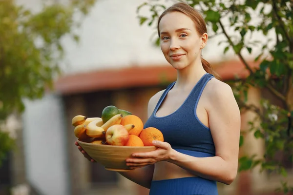 Mulher em um sportwear detém uma fruta — Fotografia de Stock