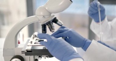 Tanımlanamayan laboratuar çalışanı mikroskop altında kan örneklerini inceliyor.