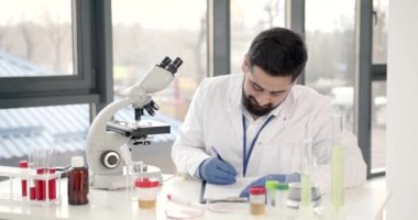 Laboratuvar erkek çalışanı mikroskopla araştırma yapıyor.