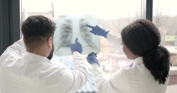 Doctor and coworker standing and looking at x-rays in clinic — Stock Video