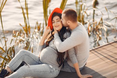 Hamile bir kadın ve kocası nehrin kenarında duruyor.