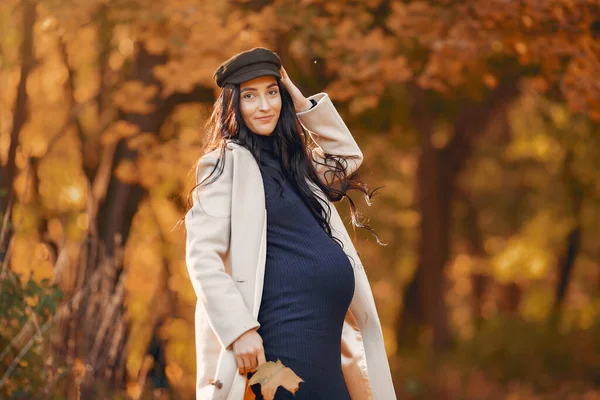 Mujer embarazada con un abrigo marrón en un parque de otoño — Foto de Stock