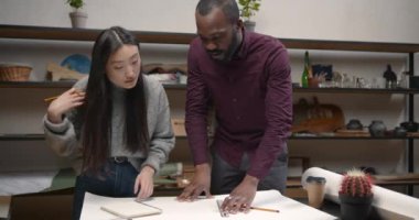 Kadın mühendis ve siyah adam eskiz ya da plan yapıyor.