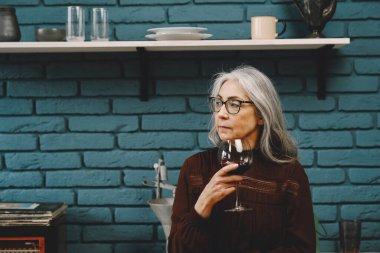 Evinde bir bardak kırmızı şarapla güzel, mutlu bir son sınıf kadınının portresi.