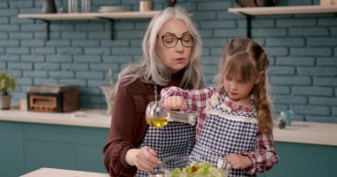 Sevimli kız ve büyükannesi mutfakta yemek pişiriyor.
