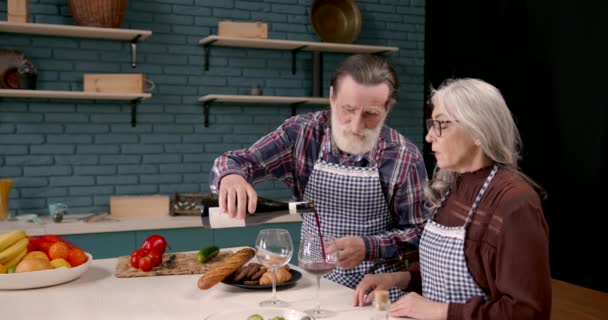 Старшая пара дегустирует вино на кухне — стоковое видео
