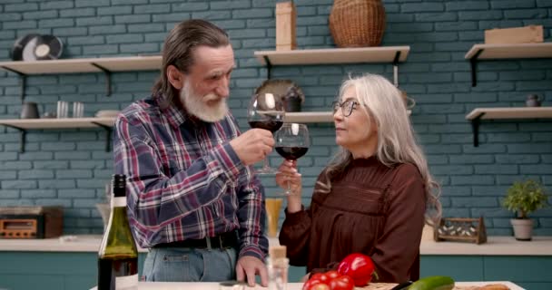 Ηλικιωμένο ζευγάρι δοκιμάζει κρασί στην κουζίνα — Αρχείο Βίντεο