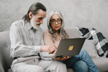 Üst düzey çift dizüstü bilgisayarlarıyla kanepede oturuyor.