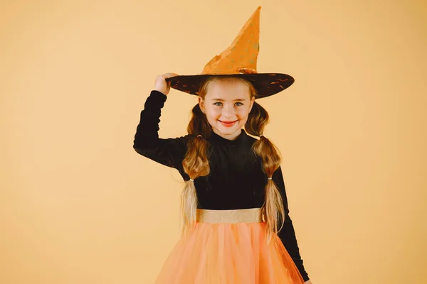 Menina bonita bruxa em um fundo laranja — Fotografia de Stock